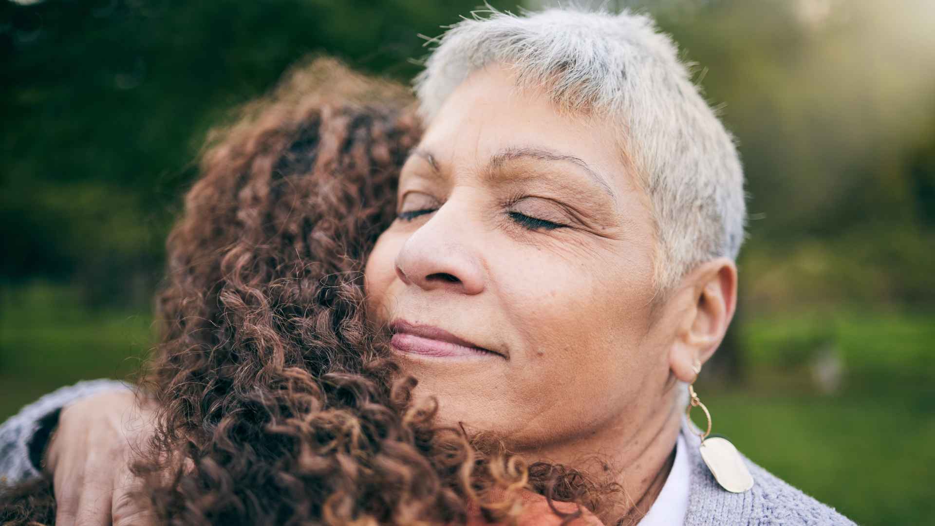 senior mother and her daughter hug at the park